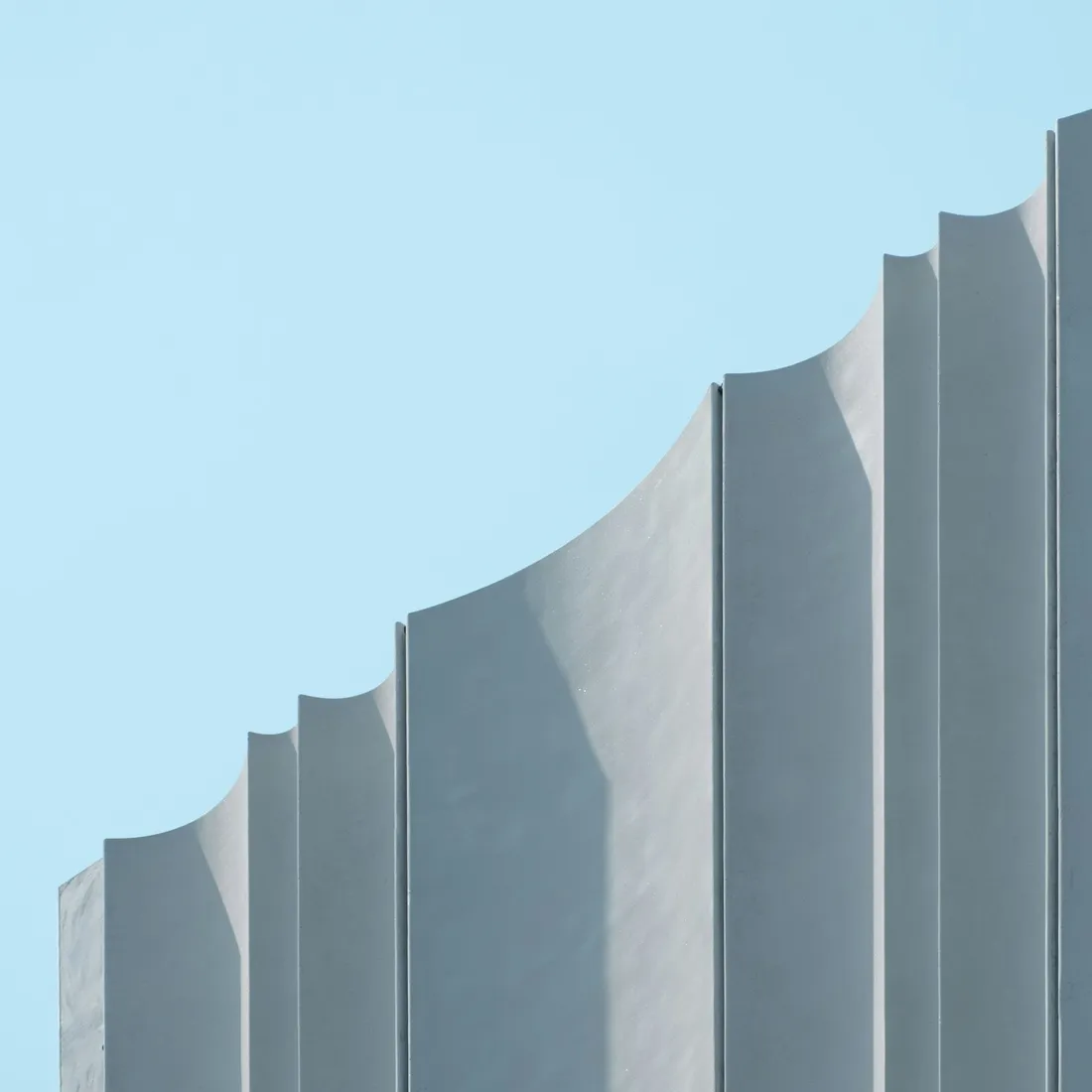 A grey concrete building rising against a clear daytime sky