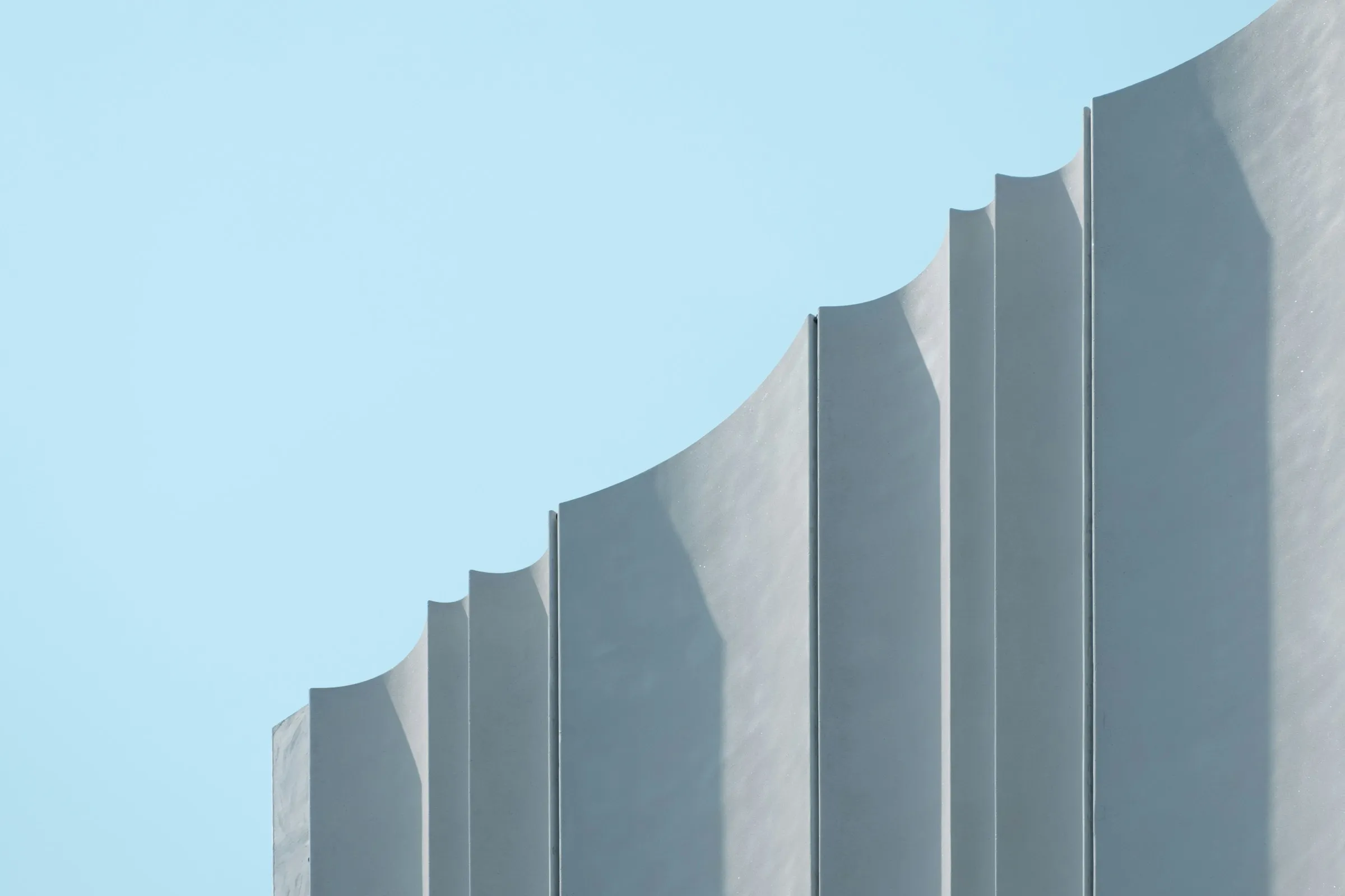 A grey concrete building rising against a clear daytime sky