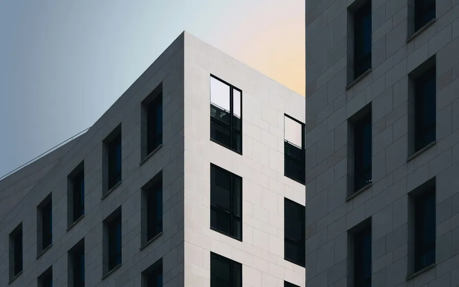 A person photographing a concrete building, camera raised towards the facade