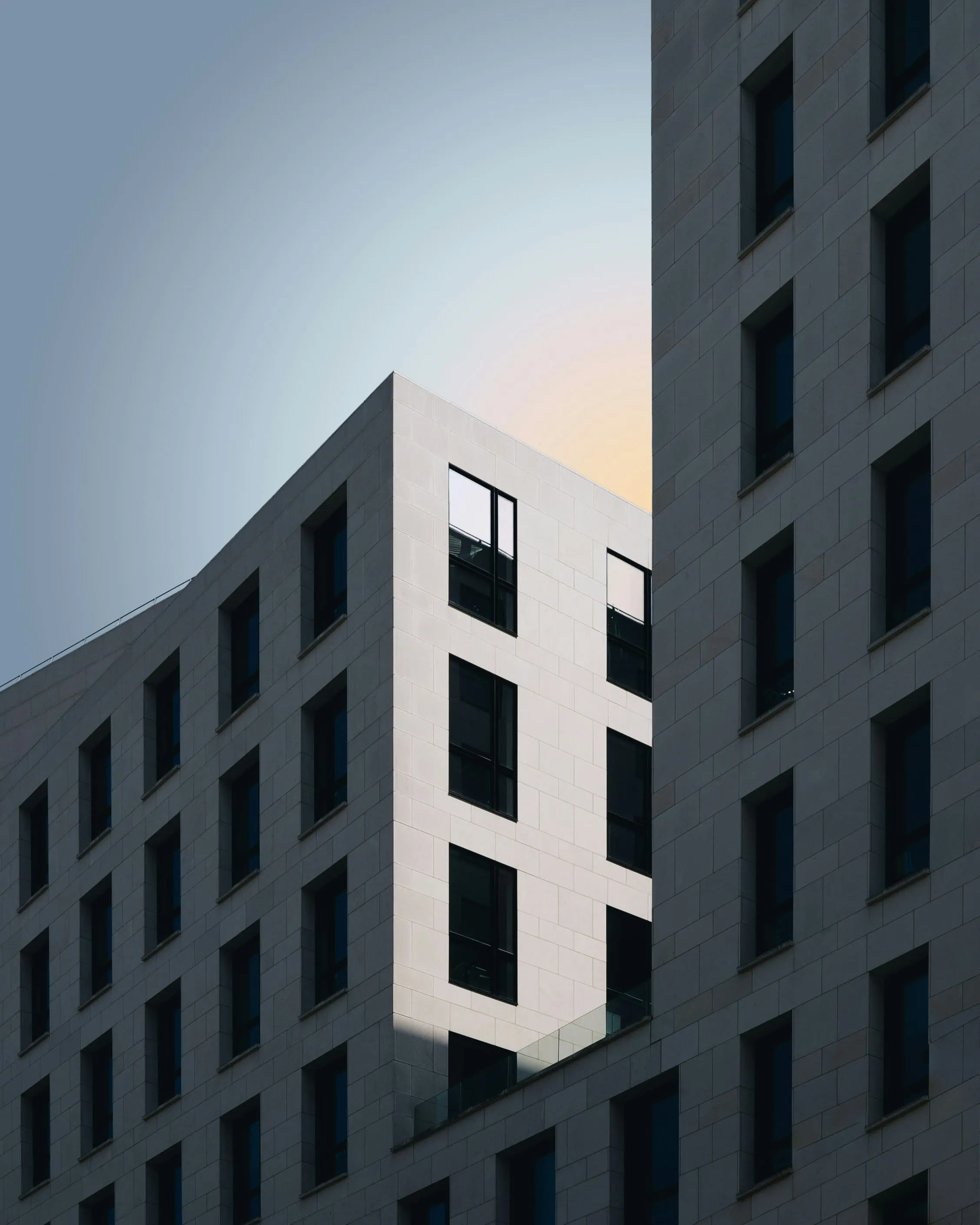 A person photographing a concrete building, camera raised towards the facade