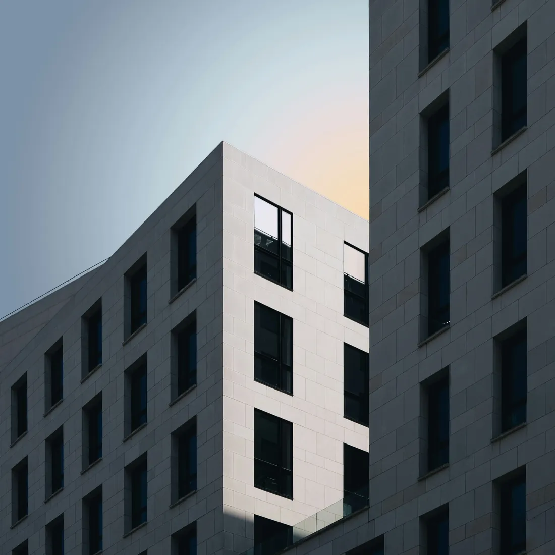 A person photographing a concrete building, camera raised towards the facade