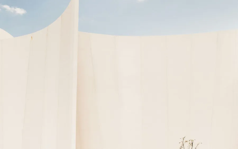A figure standing at the base of a large blank white wall