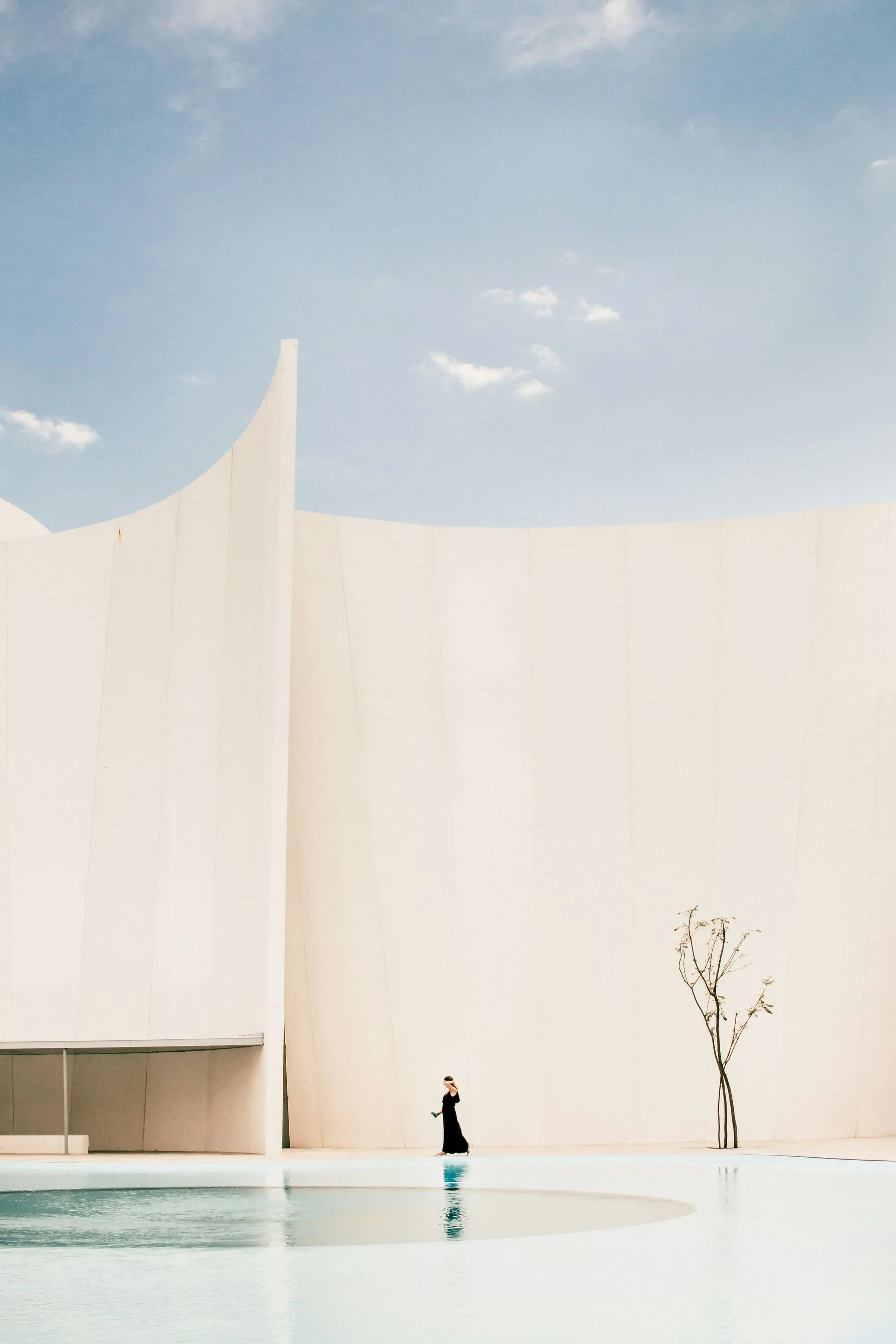 A figure standing at the base of a large blank white wall