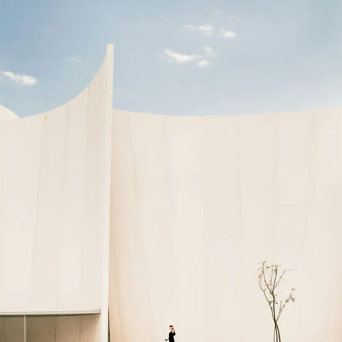 A figure standing at the base of a large blank white wall